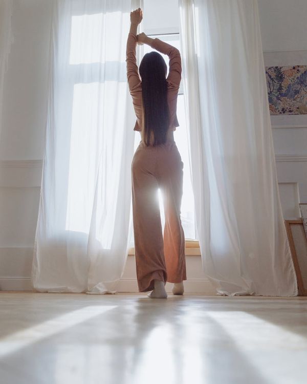 Person meditating peacefully in a minimalist room with soft, icy white light.