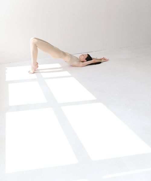 Woman in a calming yoga pose, bathed in bright turquoise light with an icy sheen.